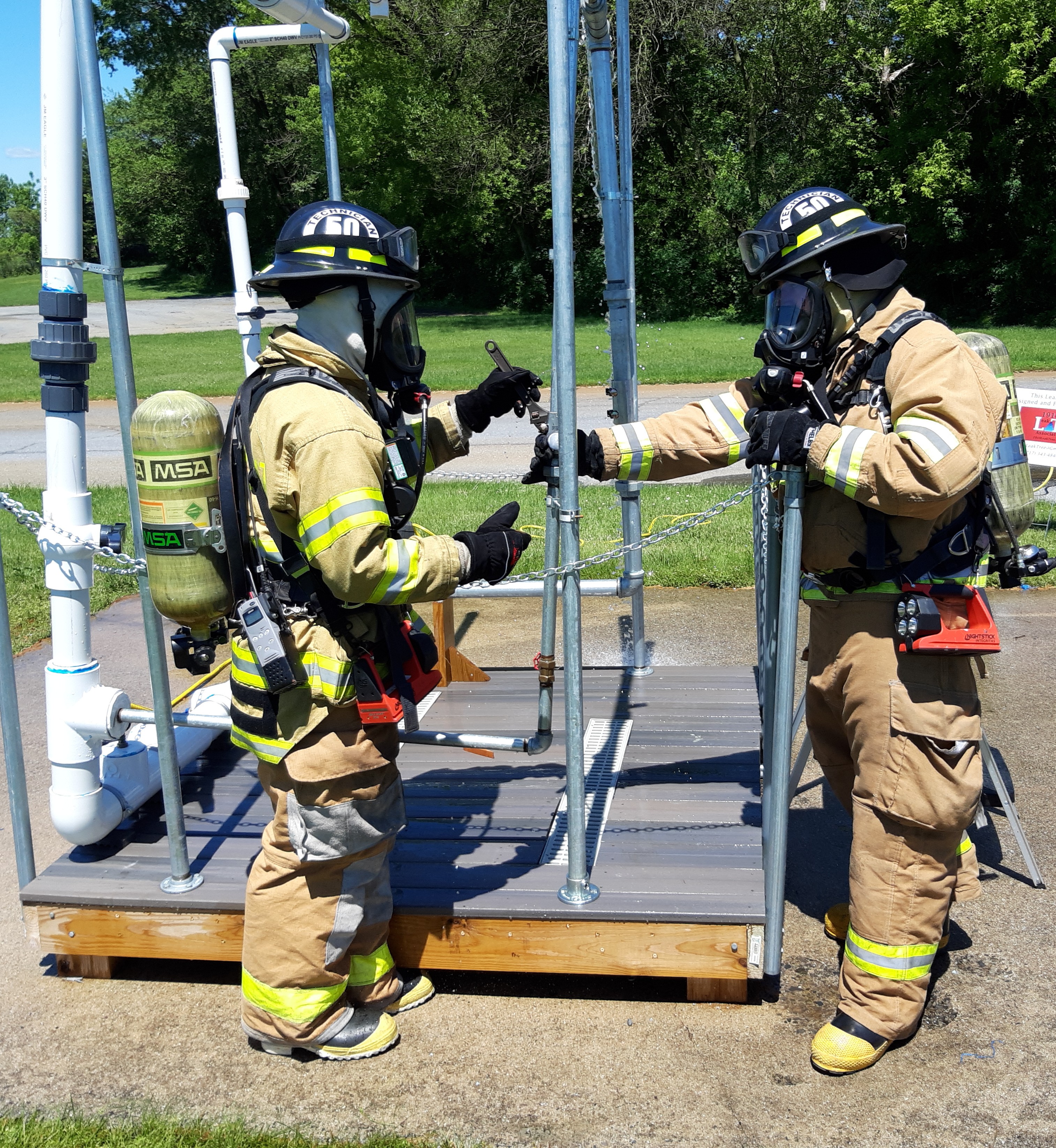 Two first responders practicing leak mitigation on our Base HazMat Leak Tree Training Prop.